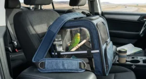 Comfortable travel bird carrier with a padded shoulder strap resting on a car seat for long trips.